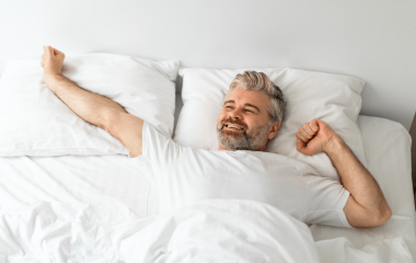 happy mature man lying in bed stretching after wa 2023 11 27 05 05 15 utc